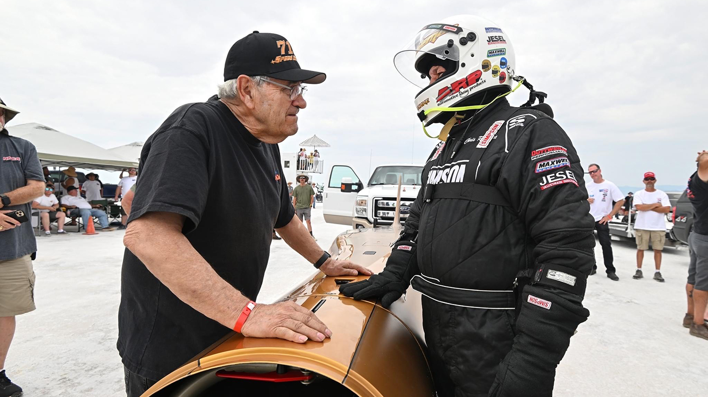 Chris Raschke talking to a crew member standing next to his land speed racer