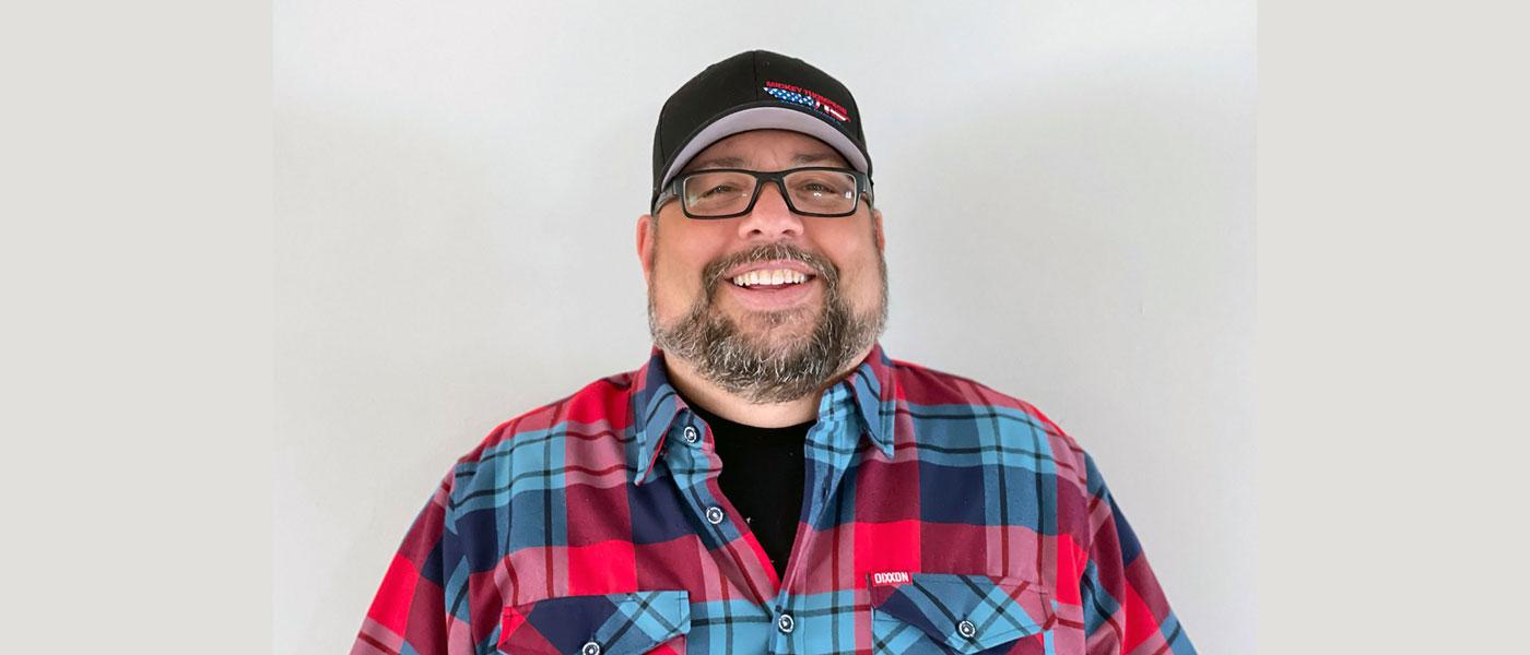 Headshot of Tom Kundrik wearing a hat and flannel shirt