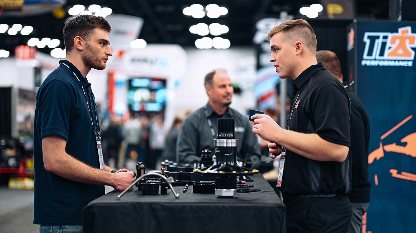 A PRI Show exhibitor talking about his products with a PRI Show attendee. 