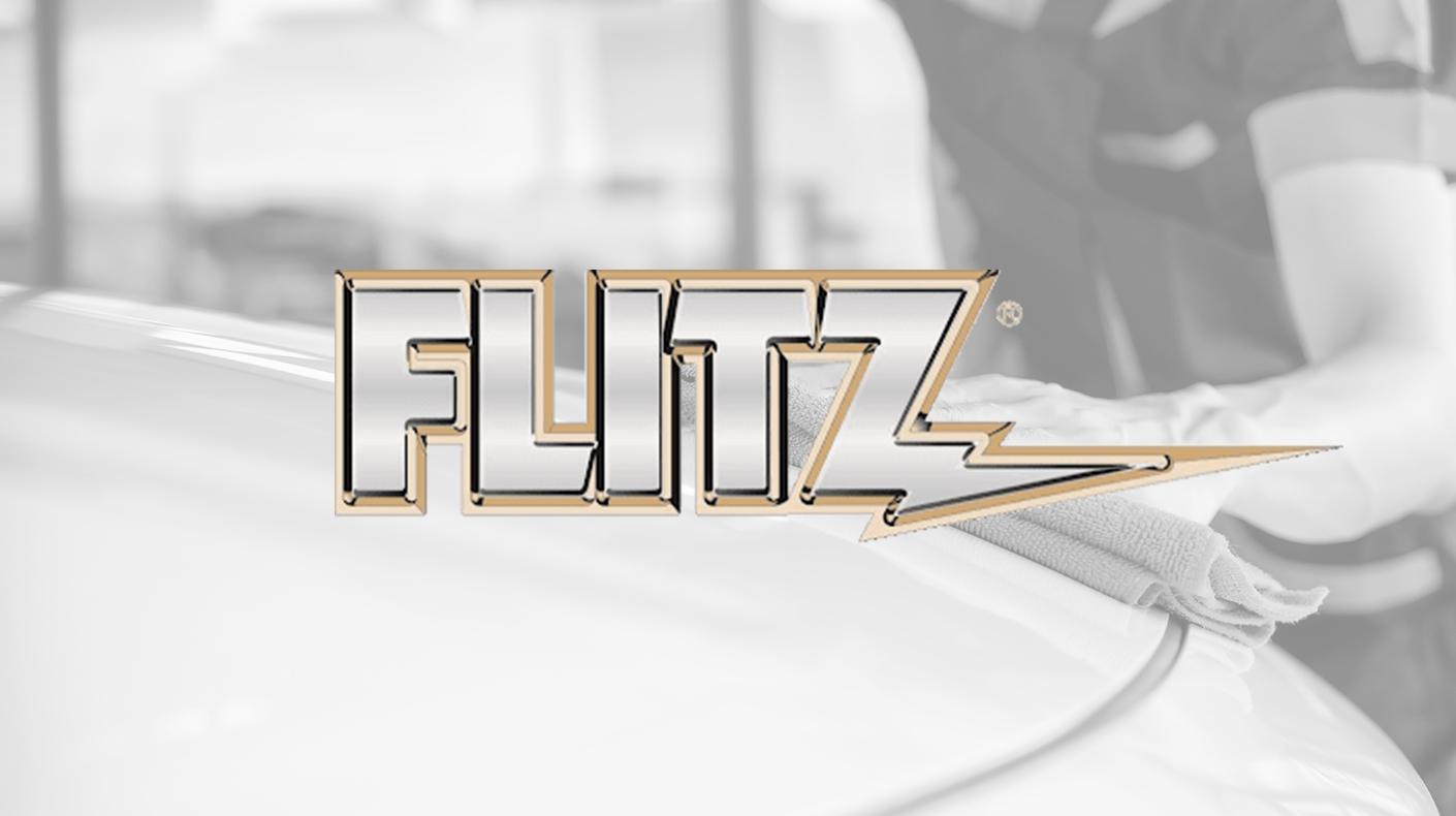 The Flitz logo over a person wiping down the hood of a car.