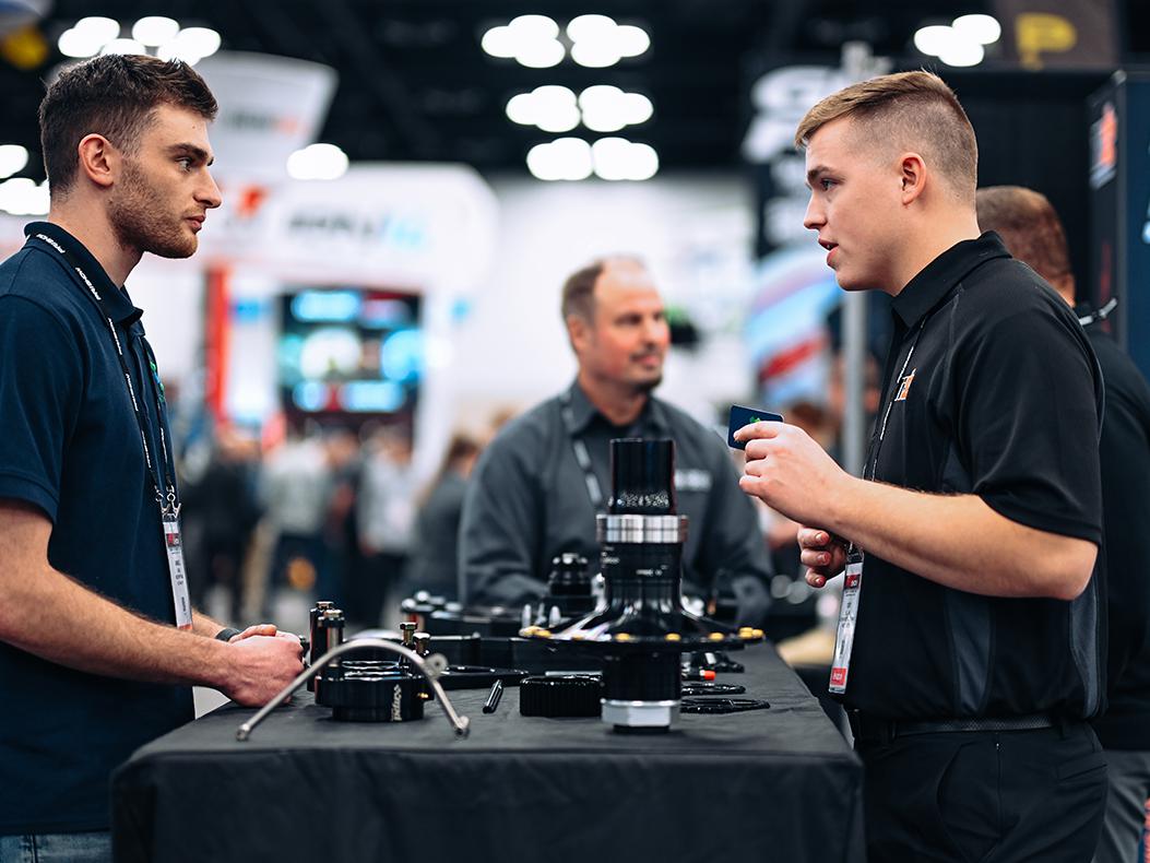 A PRI Show exhibitor talking about his products with a PRI Show attendee. 