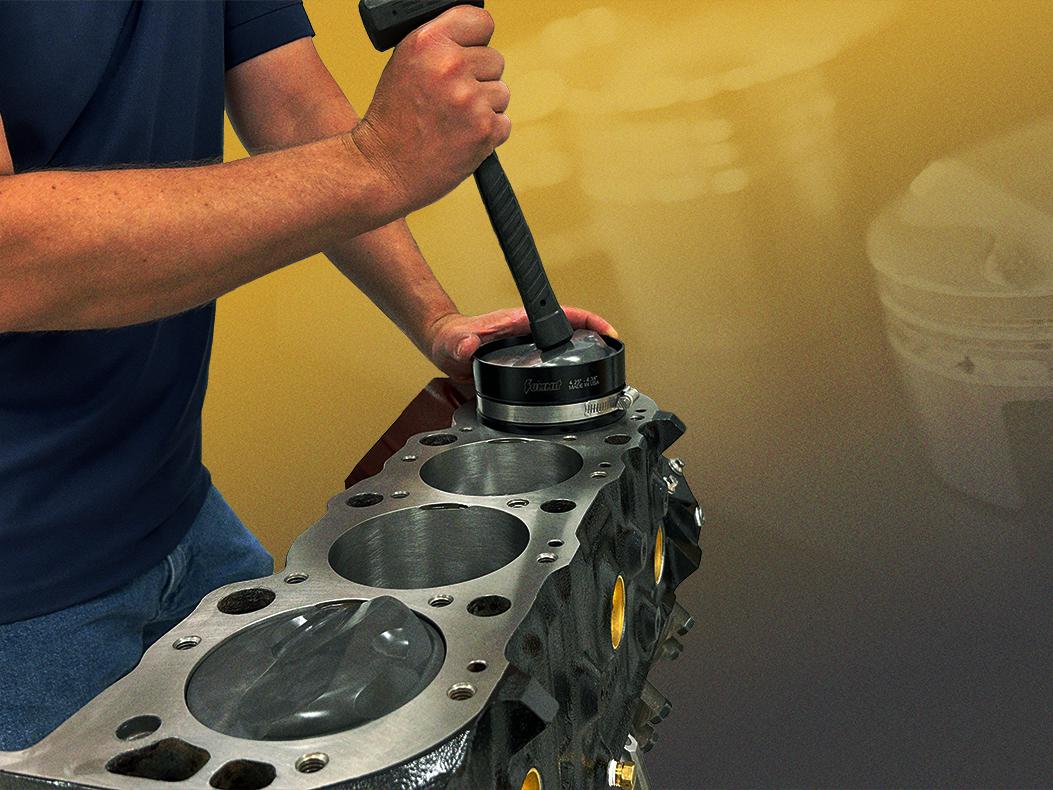 Engine builder inserting piston into cylinder.